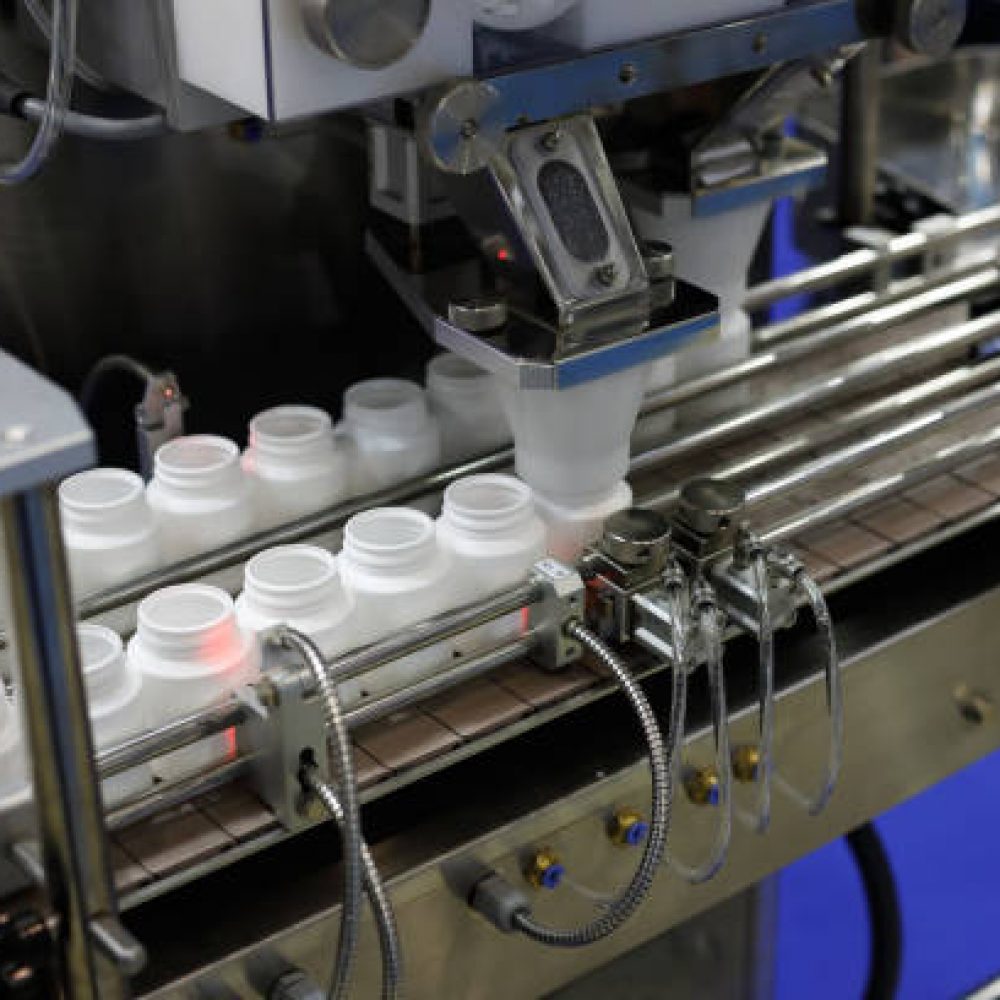 Pharmaceutical packaging line. Bottle filling machine with empty plastic pill bottles.